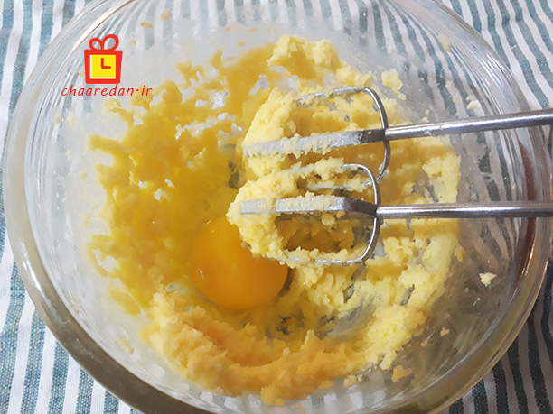 زدن تخم مرغ با پودر قند و کره در شیرینی ملکه بادام